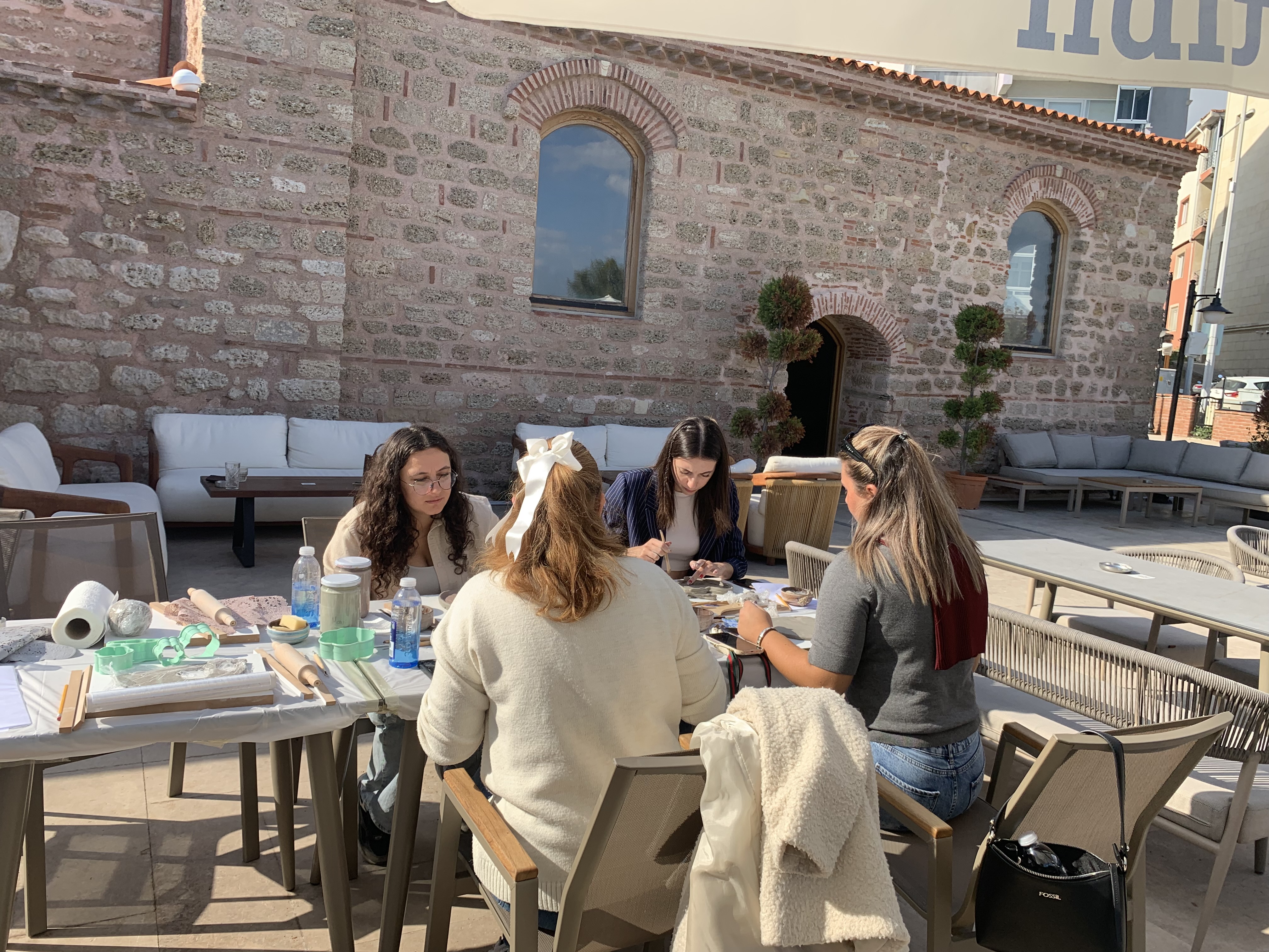 Açık havada bir masanın etrafında seramik çalışan grup.